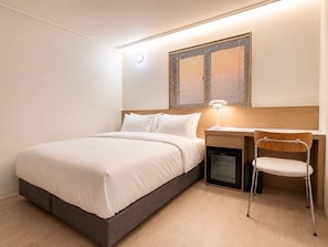 A bedroom with a bed, bedside table, lamp, and a desk with a chair. - Link B Hotel (Busan)