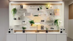 A modern room with a white console table, a wall-mounted pegboard with various items, and a small desk lamp. - Link B Hotel (Busan)