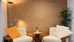 A room with two sofas, a small round table, a floor lamp, and a potted plant. - Link B Hotel (Busan)