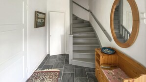 Una scala con corrimano, una panca in legno con uno specchio e un tappeto sul pavimento.
