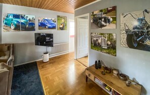 Ett vardagsrum med en tv, ett soffbord och tavlor på väggen som föreställer klassiska bilar och motorcyklar.