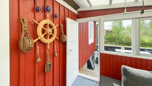 Ett rum med en röd vägg, ett träskeppsratt och nautiska dekorationer.
