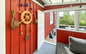 Ett rum med en röd vägg, ett träskeppsratt och nautiska dekorationer.