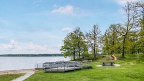 En park vid sjön med en lekplats, picknickbord och en gräsyta.