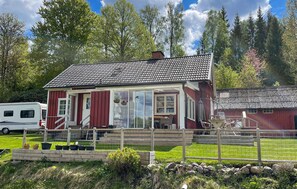A red wooden house with a tiled roof, a covered porch, and a fenced garden area. - Pet friendly home in Broaryd with WiFi (Broaryd)