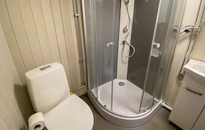 A bathroom with a toilet, a shower enclosure, and a sink.