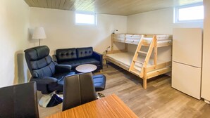 Una habitación pequeña con una litera, un sofá, una mesita y una lámpara.