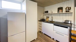 Una cocina equipada con refrigerador, microondas, pileta y gabinetes de madera.