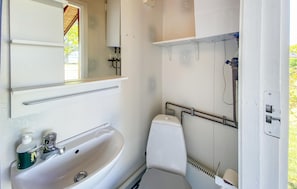 A small, white bathroom with a sink, toilet, and shower.