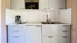Una cocina moderna con gabinetes blancos, un lavamanos de acero inoxidable y una cafetera.