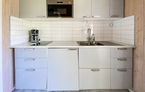 A modern kitchen with white cabinets, a stainless steel sink, and a coffee maker.