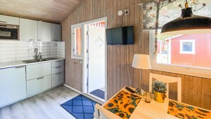 Una cocina compacta con pileta, alacenas y un televisor montado en la pared.