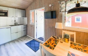 A compact kitchen with a sink, cabinets, and a television mounted on the wall.