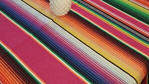 A dining area with a colorful striped tablecloth, wooden chairs, and a pineapple centerpiece. - Asinerie Kuleni (Ponteilla)