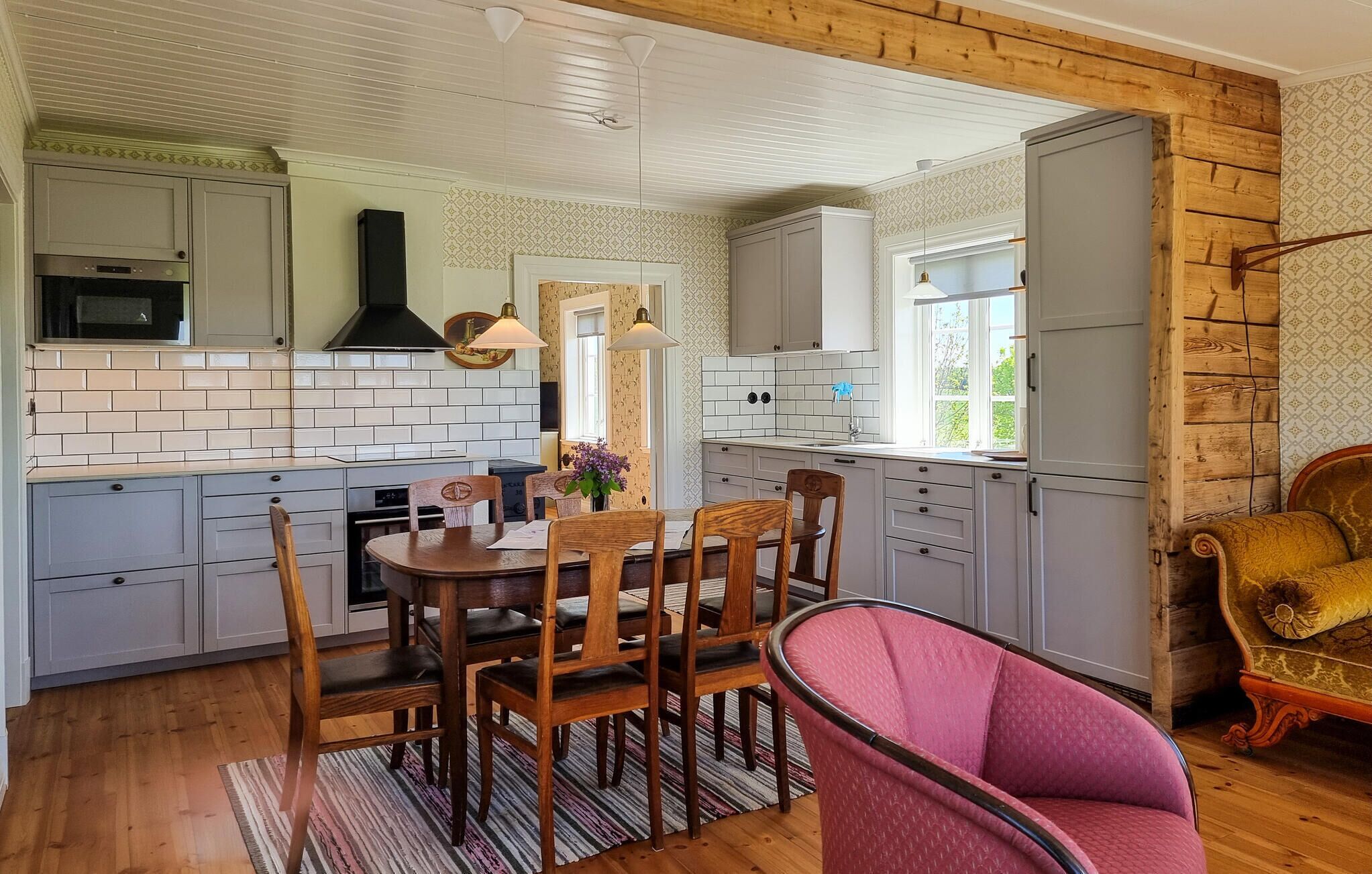 Una cucina con mobili bianchi, un tavolo da pranzo con sedie e un pavimento in legno.