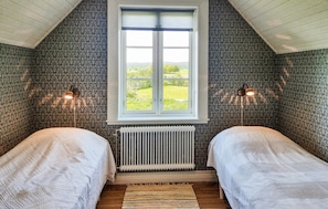 Ein Zimmer mit zwei Betten, einem Heizkörper, einem Fenster mit Blick und zwei Wandlampen.