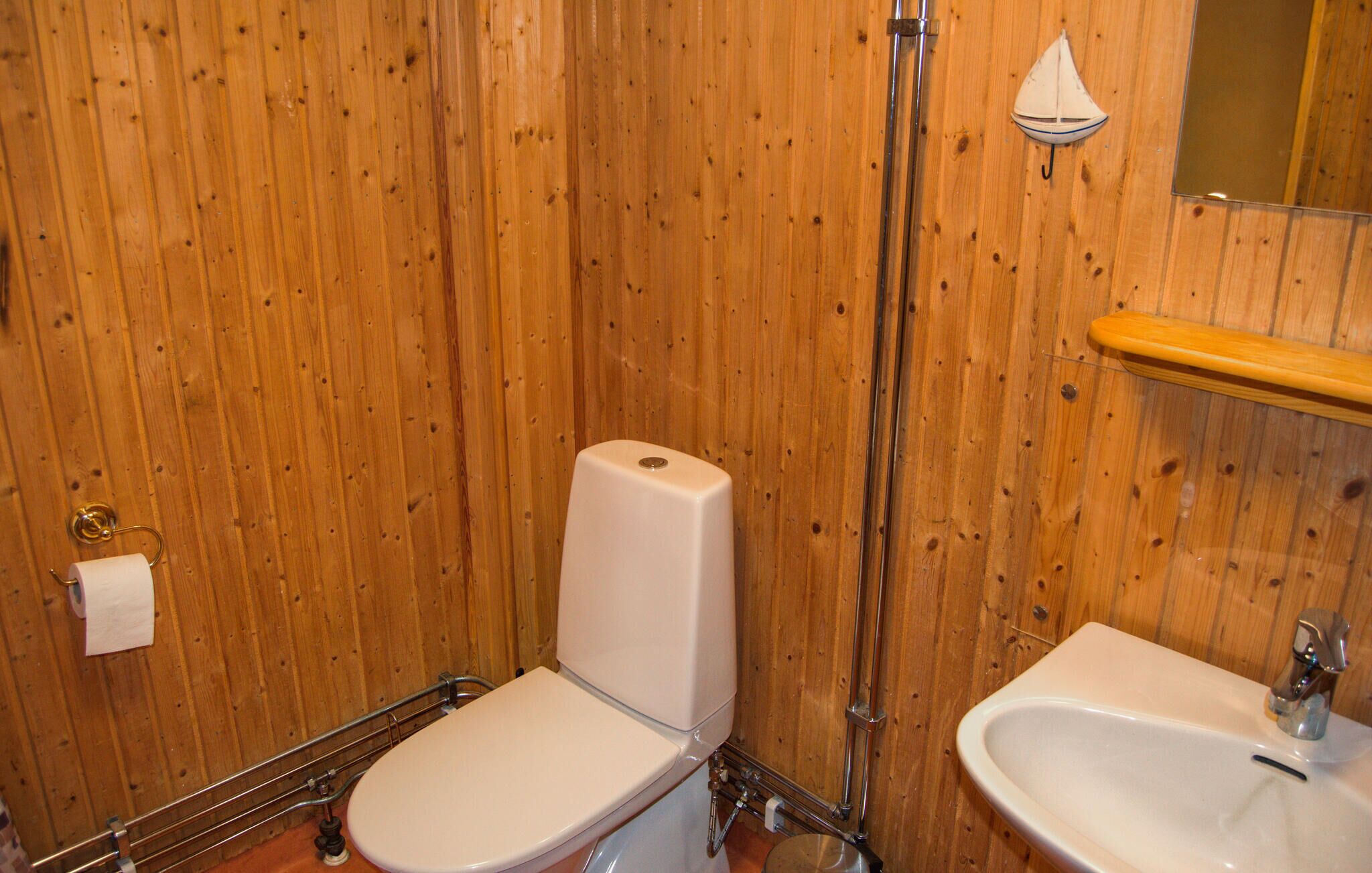 Un baño con paneles de madera, un inodoro, un bidé y un lavabo.