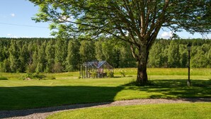A greenhouse structure in a grassy field with a large tree nearby. - 4 bedroom awesome home in Kopparberg (Kopparberg)