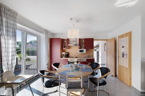 A modern kitchen with a dining area, large windows, and a view of the outdoors. - Vacation Home "Sanddüne" – Apartment Luv (Right) in Zierow (Zierow)
