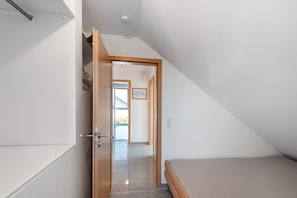 Ein Schlafzimmer mit einem Bett, einer Tür zu einem Flur und einer Deckenleuchte.