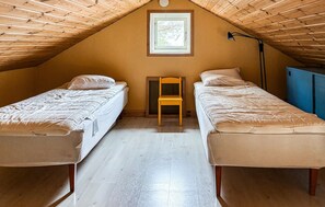 Ein Schlafsaalzimmer mit zwei Einzelbetten, einer Holzbalkendecke, einem kleinen Holzstuhl und einem Fenster mit Blick.