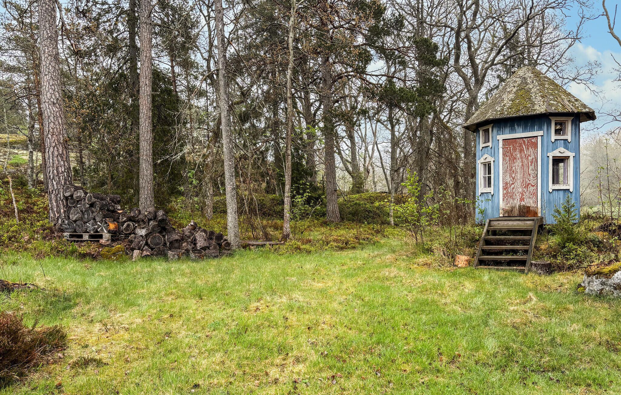 A rustic cabin with a wooden staircase leading to a door, surrounded by a forest.