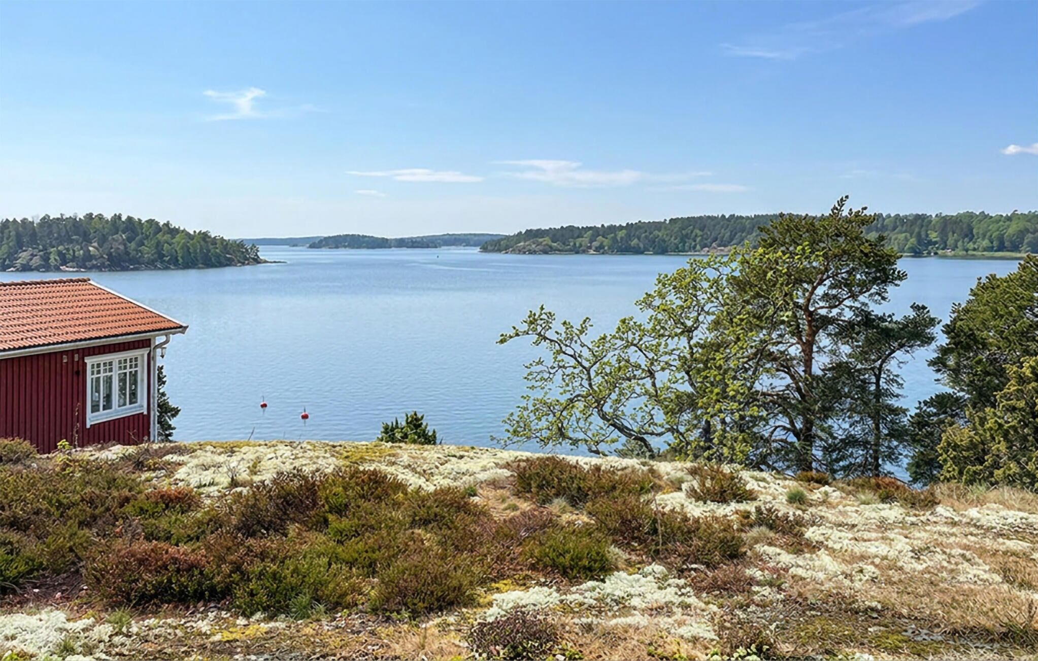 Un bâtiment rouge qui offre une vue sur un lac paisible et des collines boisées.