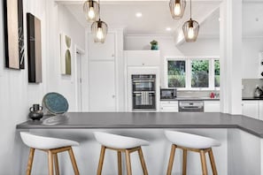 A modern kitchen with a central island, bar stools, pendant lighting, and a view of the outdoors. - Lake View 2 Bedroom 2 Bath with Parking (Hamilton)