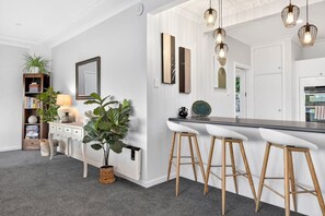 A modern kitchen with white cabinetry, a bar area with stools, and pendant lighting. - Lake View 2 Bedroom 2 Bath with Parking (Hamilton)