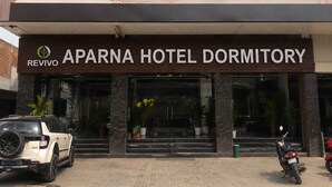 The exterior of Aparna Hotel Dormitory with a signboard, entrance, and potted plants. - APARNA HOTEL DORMITORY (Bhubaneshwar)