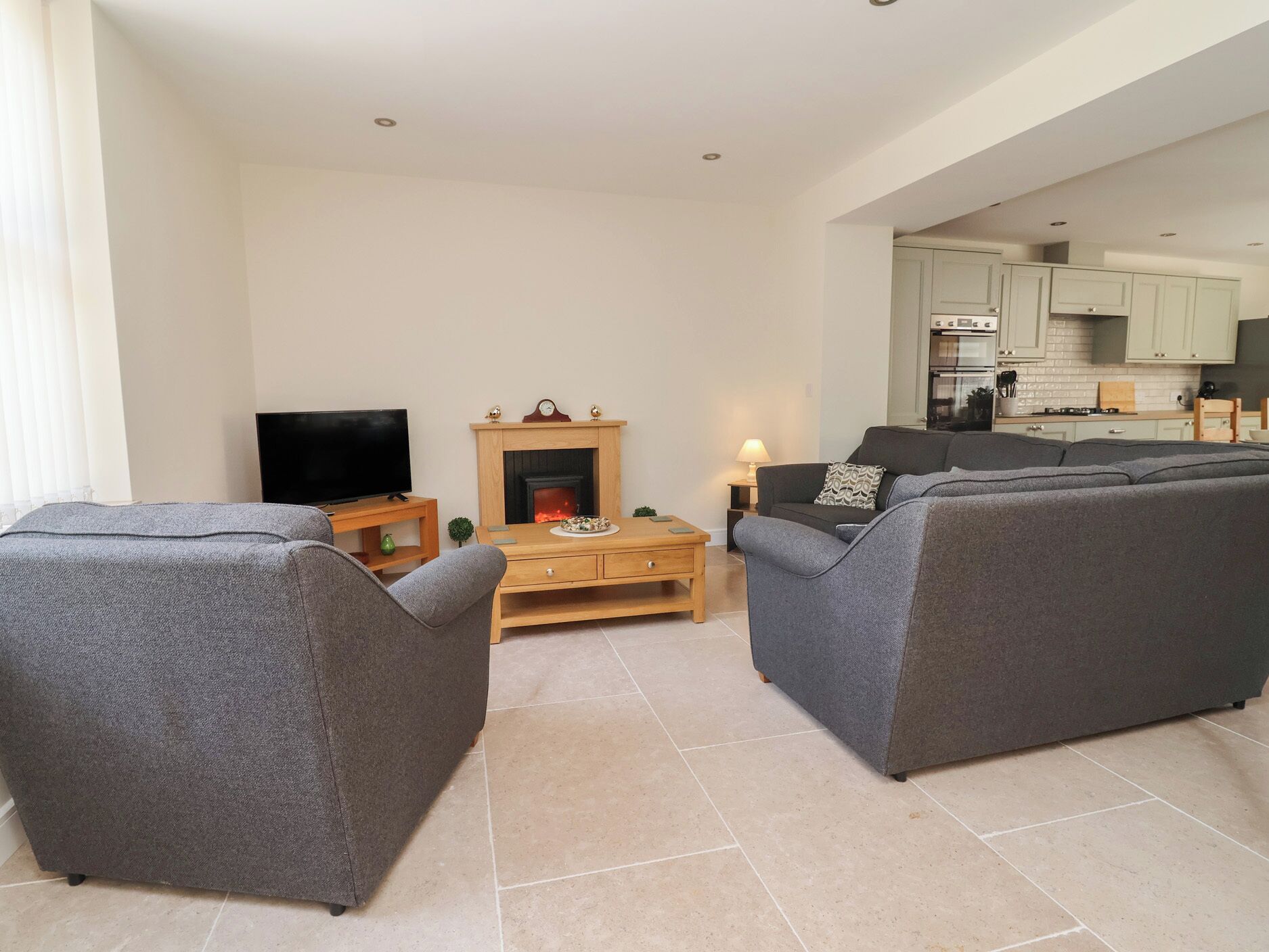 A living room with two grey sofas, a wooden coffee table, a TV, and a fireplace.