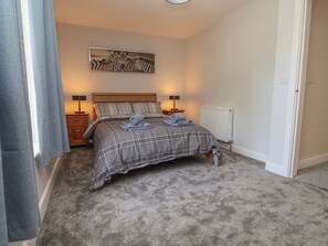 Ein Schlafzimmer mit Bett, Nachttisch, Lampe, Heizkörper und einem Wandbild mit Zebra-Motiv.