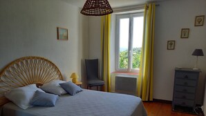 A bed with a headboard, a chair, a dresser, and a window with curtains.