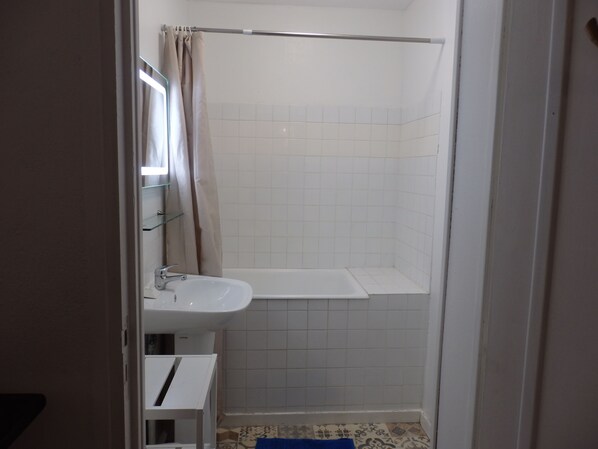 A bathroom with a shower, a sink, and a mirror.