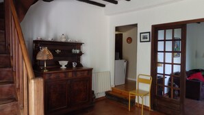 A wooden staircase, a wooden cabinet with various items, a radiator, a chair, and a door leading to another room.