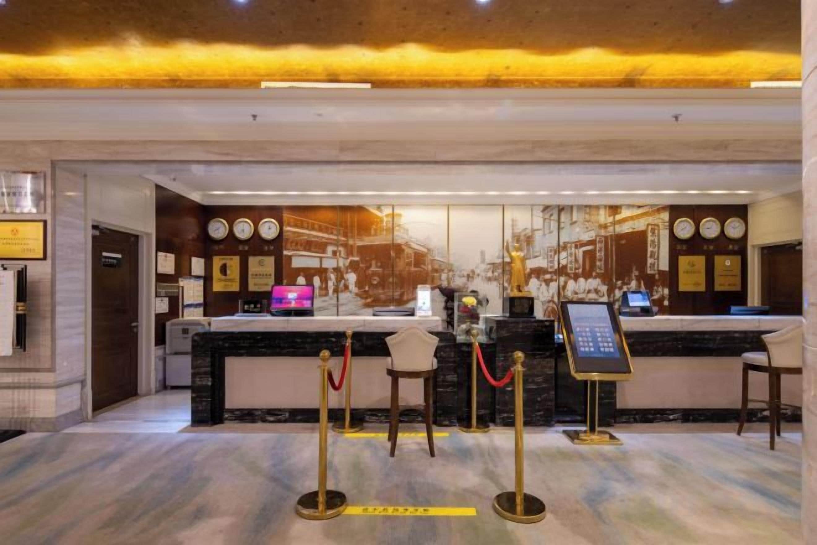 A hotel reception area with a marble counter, a reception desk, and a waiting area with chairs.