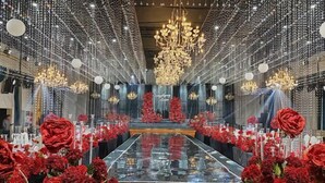 A room with a central reflective table, surrounded by red flowers and a chandelier. - Old Tram Hotel (Tianjin)