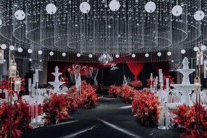 Un espace intérieur doté d’une allée centrale, de compositions florales rouges et de luminaires suspendus.