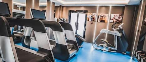 Un gimnasio con cintas de correr, una bicicleta estática y una máquina de remo.