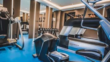 Un gimnasio con equipamiento de ejercicios, incluyendo una cinta de correr, elíptica y pesas.