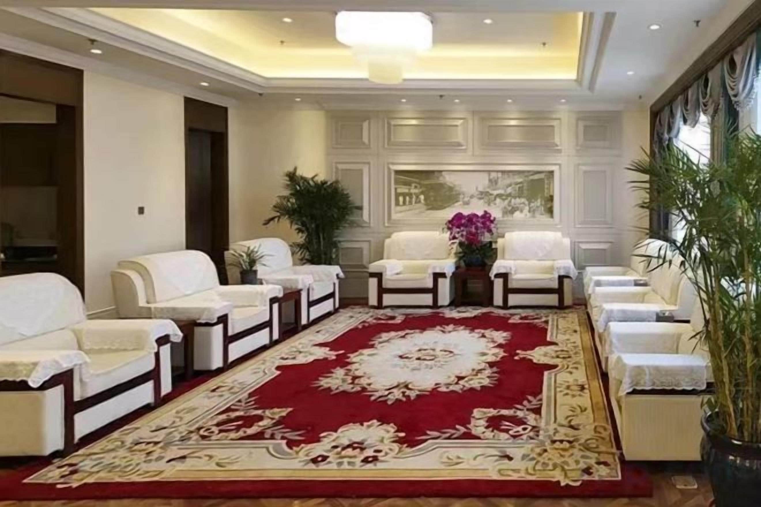 A hotel lobby with a red carpet, white sofas, and a large mirror.