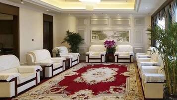 A hotel lobby with a red carpet, white sofas, and a large mirror.