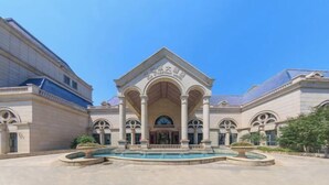 A building with a central entrance, arched columns, and a fountain. - Old Tram Hotel (Tianjin)
