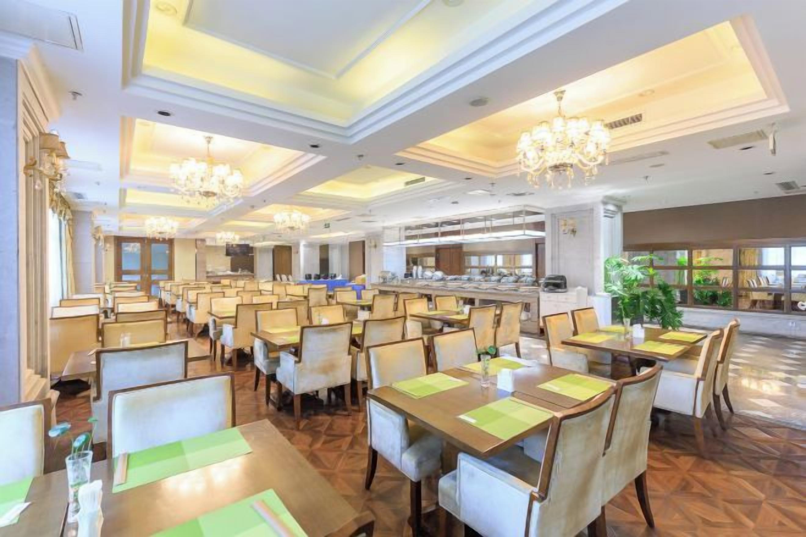 A spacious dining area with multiple tables and chairs, a central bar area, and a view of the kitchen in the background.