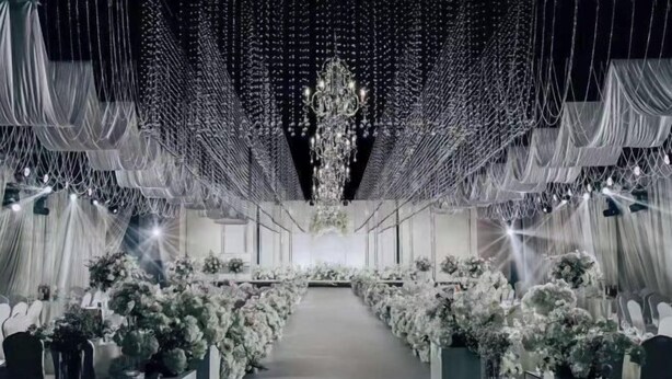 A venue with a central aisle, draped fabric, and floral arrangements. - Old Tram Hotel (Tianjin)