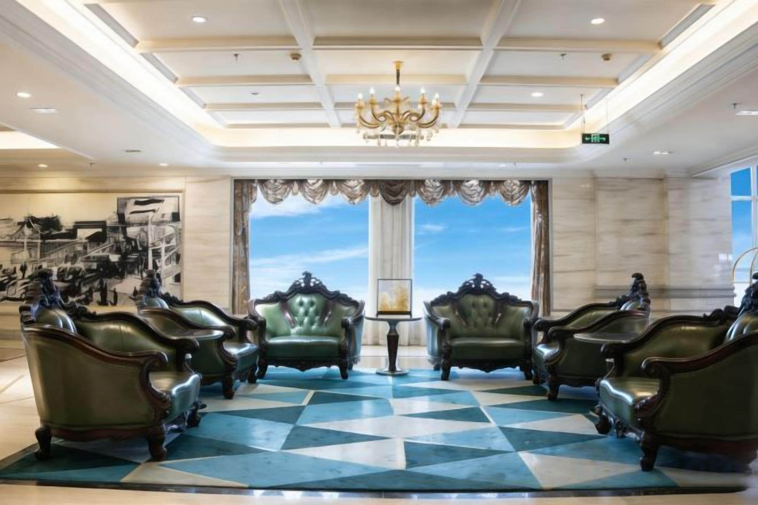 A lobby with a checkered floor, a chandelier, and a large window with a view.