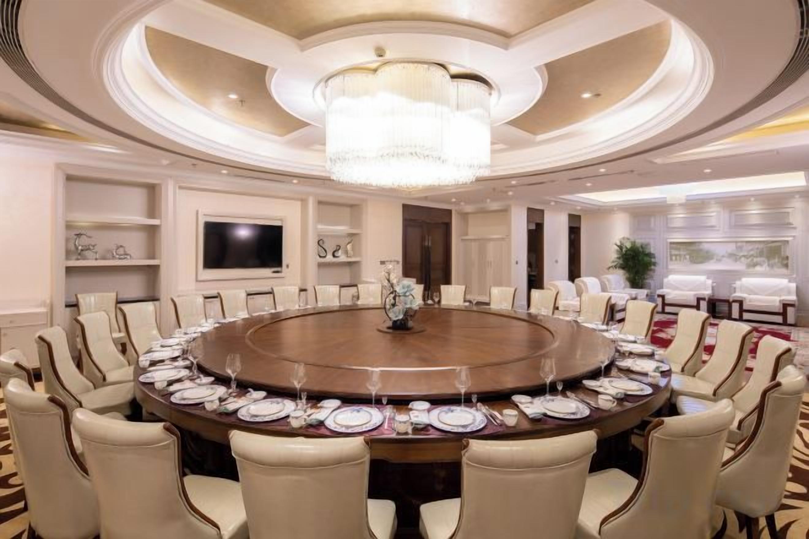 A conference room with a round table, chairs, and a chandelier.