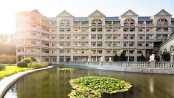A multi-story hotel with a courtyard featuring a pond with lily pads.