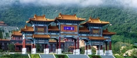 A traditional Chinese gate with multiple arches, set against a mountainous backdrop.