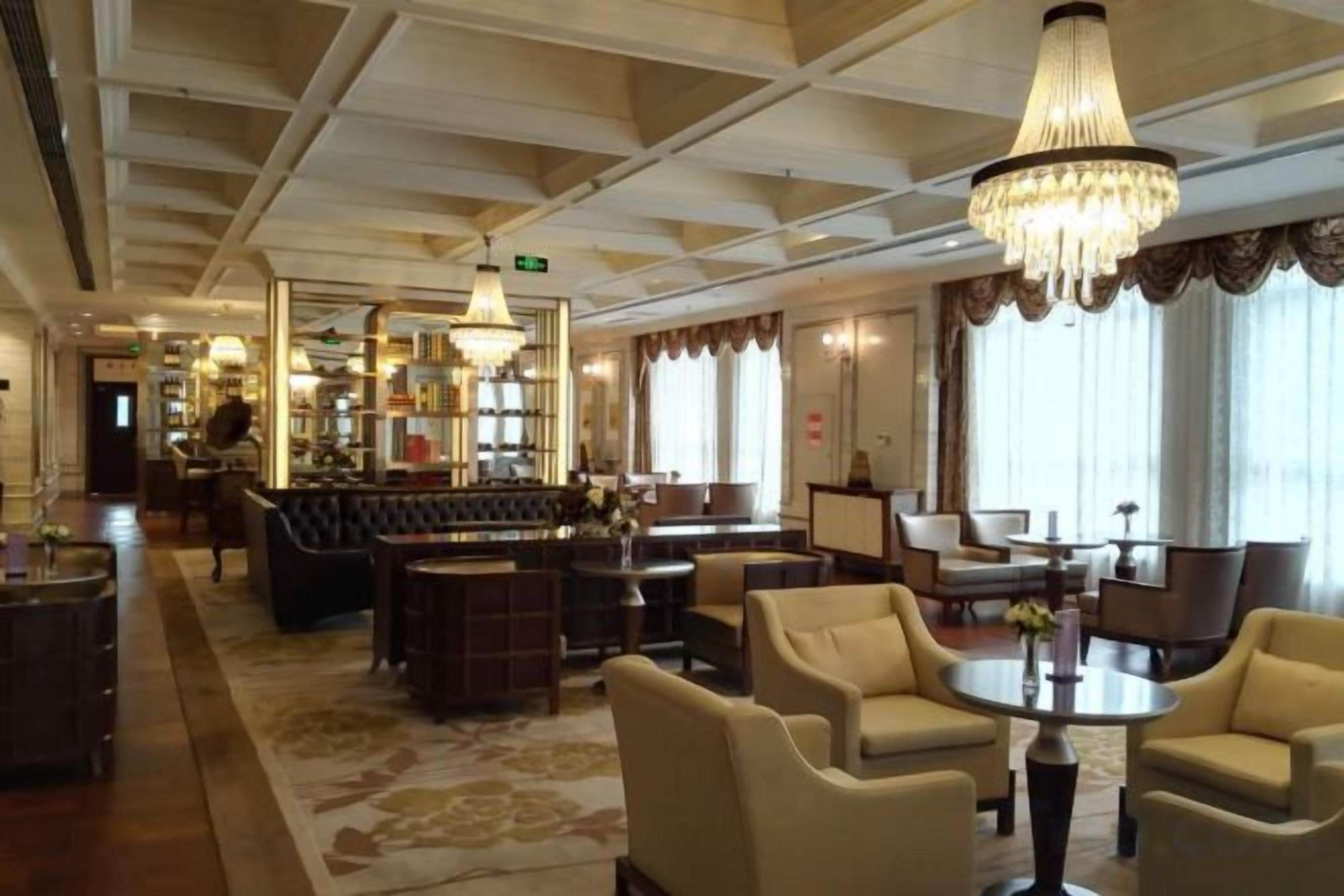 A hotel lobby with a bar area, seating arrangements, and a chandelier.
